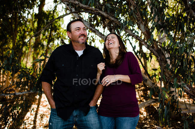 Esposo y esposa riéndose bajo el árbol en Chula Vista - foto de stock