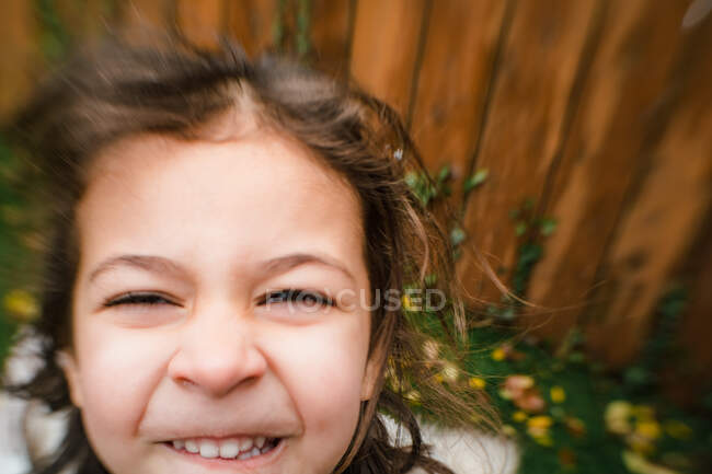 Крупним планом маленька дівчинка посміхається зовні з ефектом розмиття лінз — стокове фото