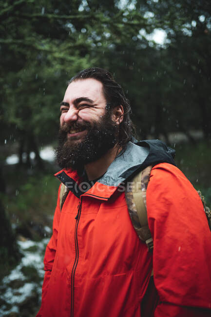 Бородатий чоловік в природі під час сніжного дня посміхається щасливо — стокове фото