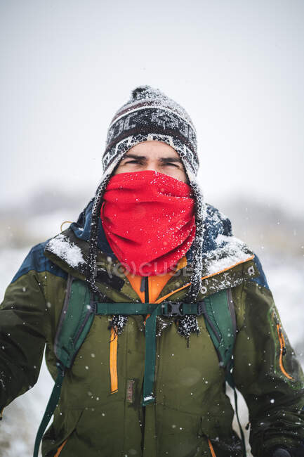 Человек с закрытым лицом идет под сильным снегом — стоковое фото