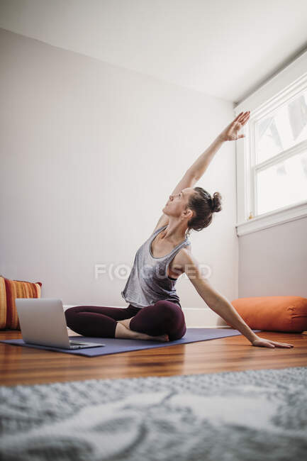 Woman practicing  yoga with laptop computer at  her home — Stock Photo