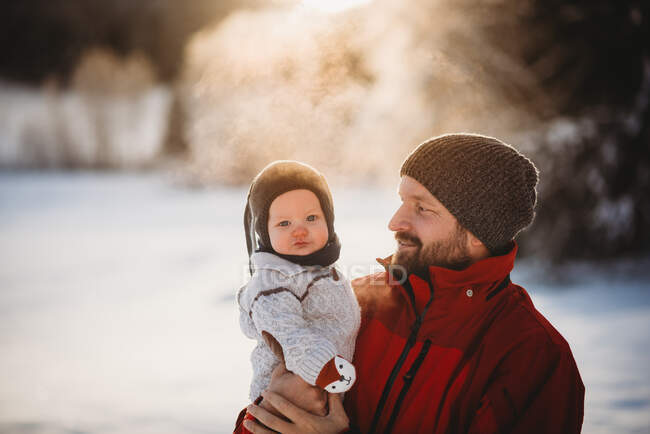 Papà e bellissimo bambino fuori nella neve in inverno durante il tramonto dorato — Foto stock