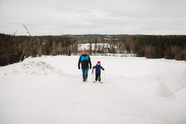 Батько і син піднімаються схилом з лижами у сніжний зимовий день Норвегія — стокове фото