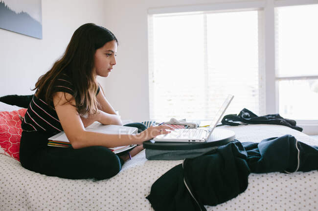 Профиль девушки, работающей над ноутбуком во время карантина — стоковое фото