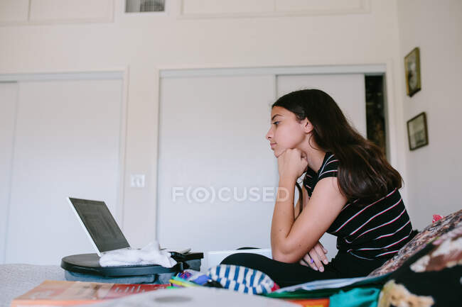 Perfil de una chica adolescente en su computadora portátil durante la escuela en línea - foto de stock