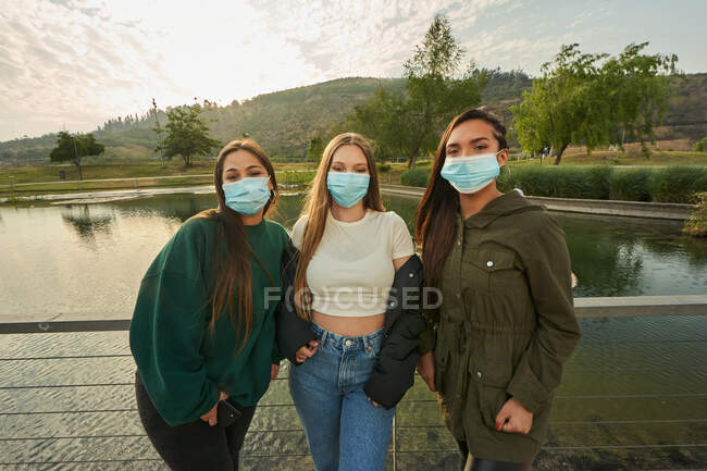 Un grupo de hermosos jóvenes amigos posando y usando máscaras en un parque - foto de stock