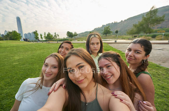 Un groupe d'amis essayant de prendre un selfie à travers leur téléphone portable dans — Photo de stock