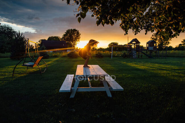 Little boy playing during sunset on picnic table — Stock Photo