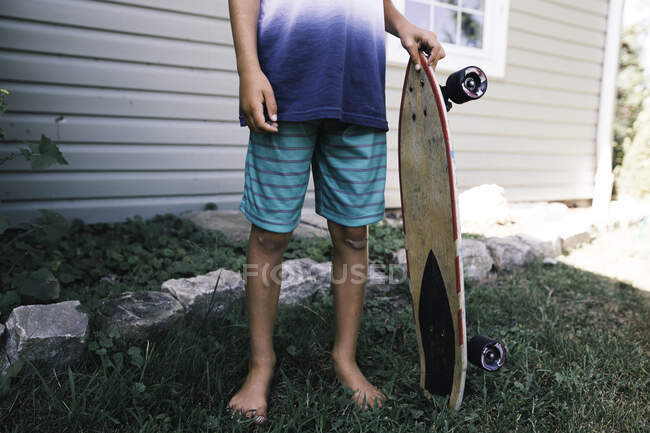 Безликий образ ребенка, держащего скейтборд — стоковое фото
