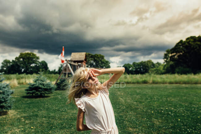 Дівчина дивиться в небо в вітряний і похмурий день — стокове фото