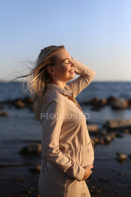 Happy pregnant woman close-up by the sea in summer. — Stock Photo