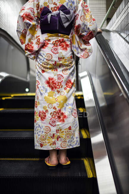 Mujer joven con un kimono japonés en escaleras mecánicas - foto de stock