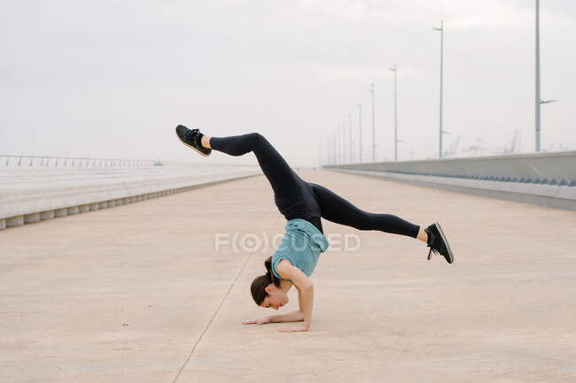 Спортивна дівчинка, танцюючи на вулиці, тримає ручну стійку. — стокове фото