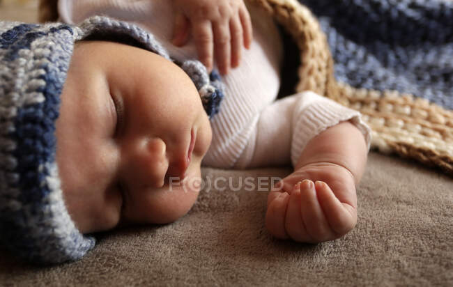 Sweet newborn baby boy with chubby cheeks sleep in bed in knitted hat — Stock Photo
