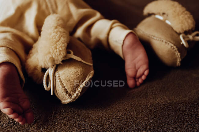 Toes of newborn baby with beige sheepskin booties and thermo pants — Stock Photo