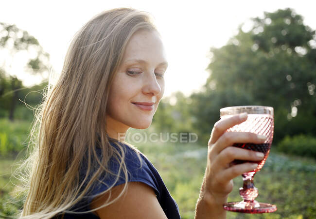 Блондинка на природі тримає келих вина на пікніку — стокове фото