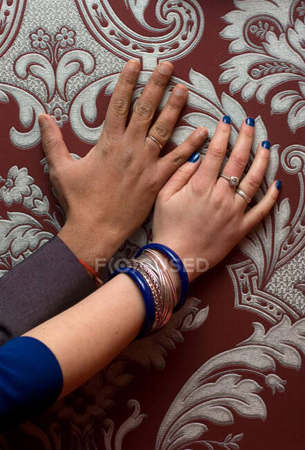 Just married multiracial couple hands with rings on wallpaper — Stock Photo