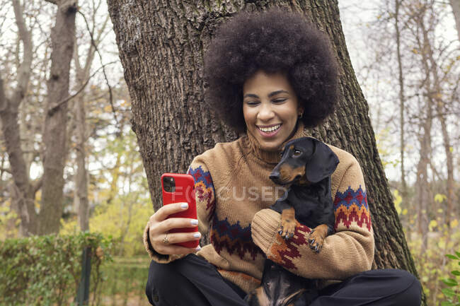 Una chica cubana tomando una selfie con su salchicha en el parque - foto de stock