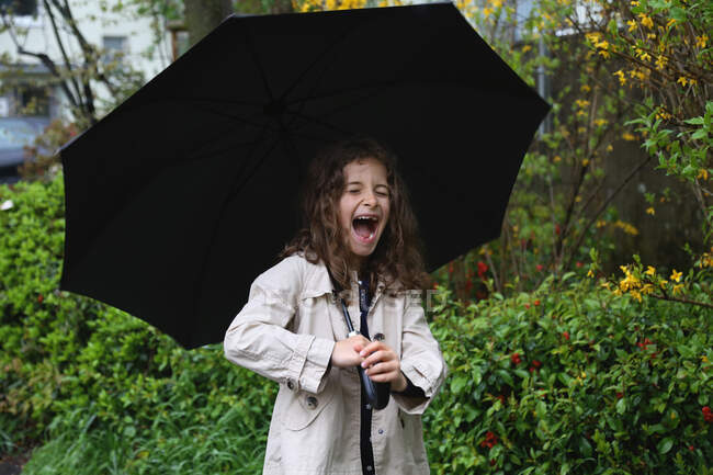 Дівчина з довгим кучерявим волоссям під парасолькою посміхається широко . — стокове фото
