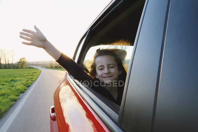 The girl in the car stuck her hand out into the wind. Travel. — Stock Photo