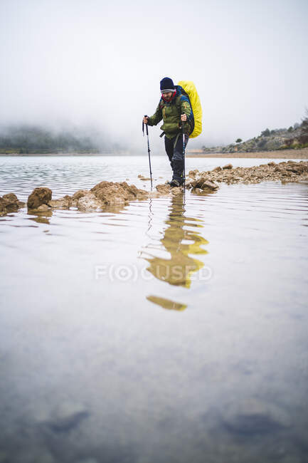 Пеший турист пересекает реку на отмели — стоковое фото