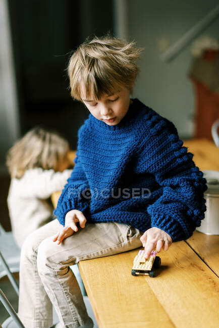Ragazzino in maglione uncinetto fatti in casa giocare con blocchi di costruzione — Foto stock
