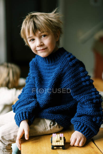 Niño en suéter de ganchillo casero jugando con bloques de construcción - foto de stock