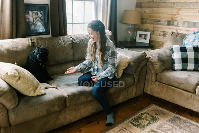 Young woman spending time and playing with her black poodle puppy dog — Stock Photo