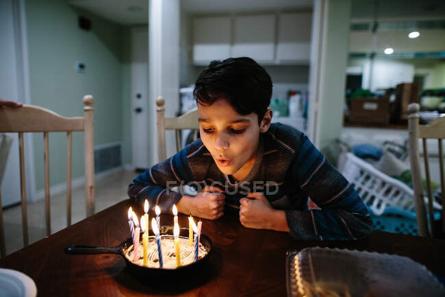 Menino sopra fora as velas no seu ferro fundido panela aniversário bolo — Fotografia de Stock