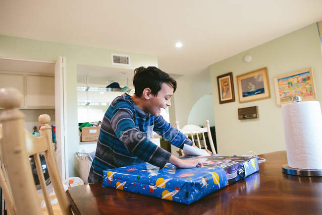 Boy Smiles Excitedly As He Opens Up His Birthday Present — Stock Photo