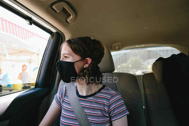 Chica adolescente sentada en el coche conduciendo a través de la graduación de la escuela media - foto de stock