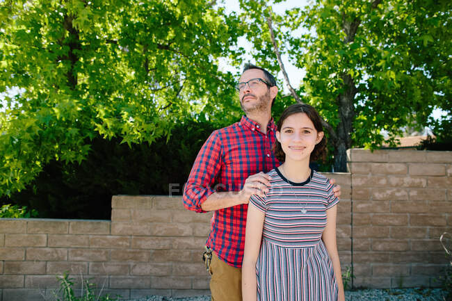 Orgulhoso pai com as mãos nos ombros fica atrás da filha adolescente — Fotografia de Stock