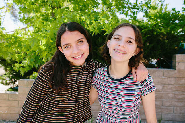 Adolescente y Tween hermanas usando rayas sonrisa para la cámara - foto de stock