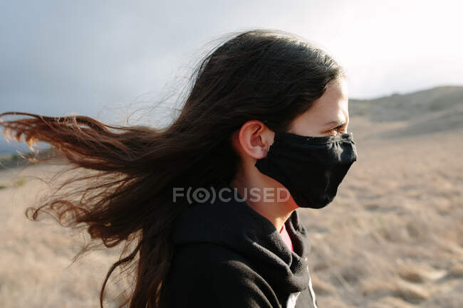 Perfil tiro de uma menina Tween vestindo uma máscara facial em um dia ventoso — Fotografia de Stock