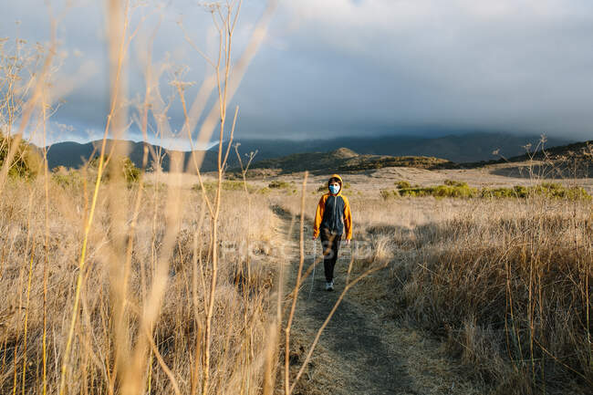 Brosse sèche encadre un garçon marchant sur un sentier de randonnée au soleil — Photo de stock