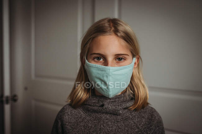 Chica con máscara facial mirando a la cámara durante la pandemia de Covid-19 - foto de stock
