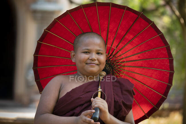 Porträt eines Novizenmönchs mit rotem Regenschirm, Bagan, Mandalay Region, Myanmar — Stockfoto