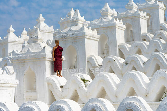 Монах-новичок, стоящий в белой пагоде Синбюме (также известной как пагода Мятеиндан), Мингун, Мандалай, поселок Сагаин, район Сагаин, регион Сагаин, Мьянма — стоковое фото