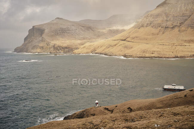 Faro a lo largo del océano en las Islas Feroe - foto de stock