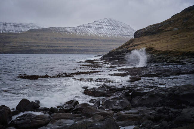Onde oceaniche che colpiscono la costa rocciosa nella città di Funningur nelle Isole Faroe — Foto stock