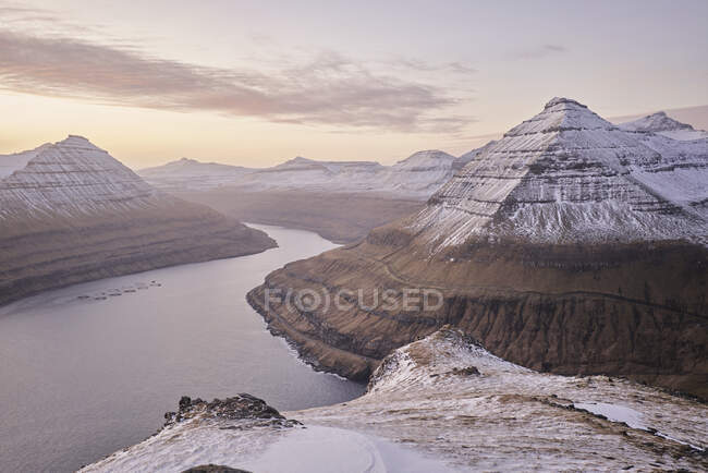 Snowy mountains rising from ocean at sunrise in the Faroe Islands — Stock Photo