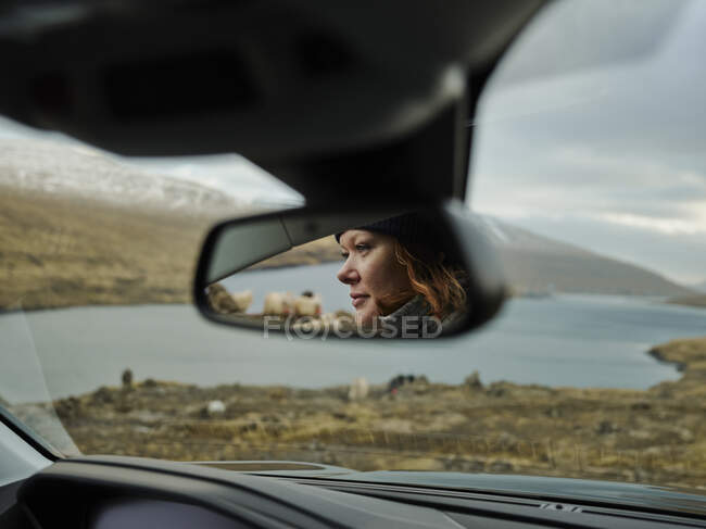 Frau schaut Schafe im Auto durch Rückspiegel an, auf den Färöer-Inseln — Stockfoto