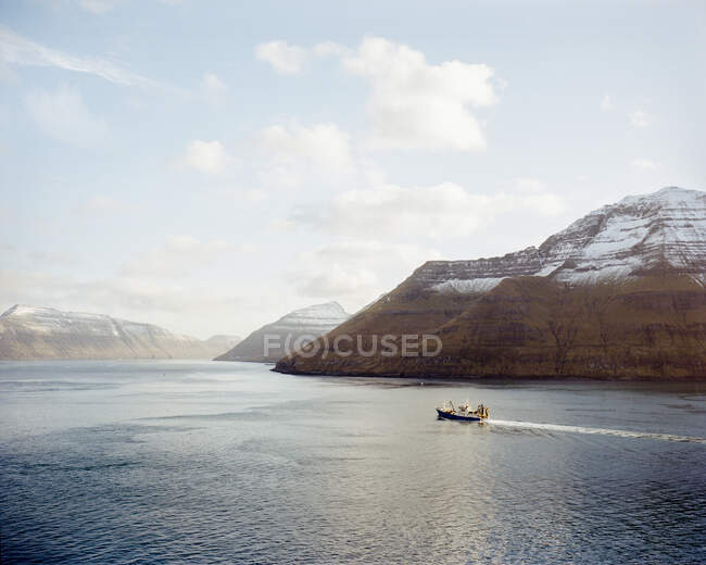 Barco que va entre dos montañas en las Islas Feroe - foto de stock