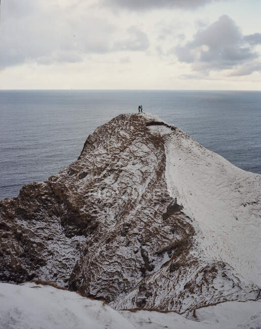 Zwei Menschen stehen am Rand einer schneebedeckten Klippe auf den Färöern — Stockfoto