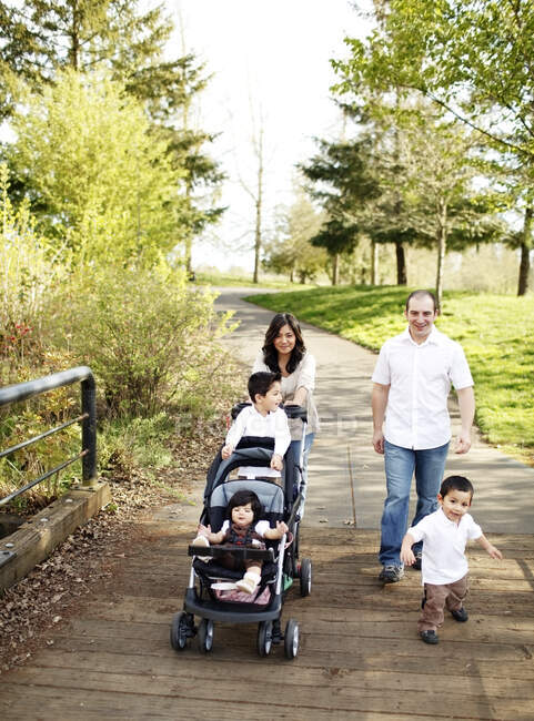 Family walking across park bridge — Stock Photo