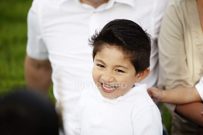 Primer plano del niño sonriendo mientras está en los brazos del padre - foto de stock