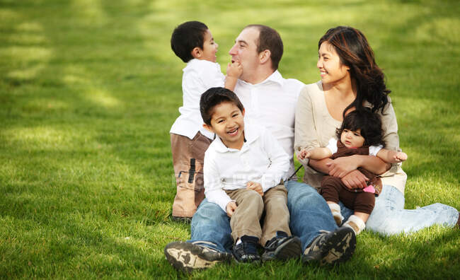 Familiy sitting in the grass in park — Stock Photo
