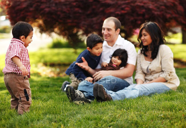 Família sentada na grama no parque — Fotografia de Stock