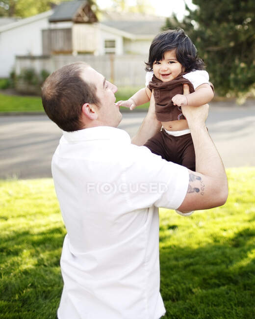 Батько тримає дочку в повітрі в парку — стокове фото