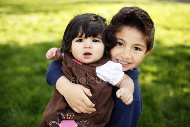 Kleiner Junge und seine kleine Schwester schauen in die Kamera, im Park — Stockfoto